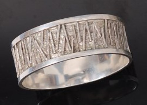 Lot 92 - A 1970s silver bangle, having outer relief...