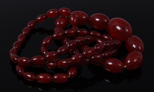 Lot 2115 - A beaded and graduated cherry amber necklace,...