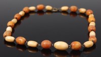 Lot 2169 - A beaded butterscotch amber and ivory single...