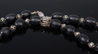 Lot 2060 - A beaded black glass necklace having pierced...
