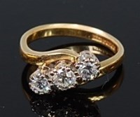 Lot 2179 - An 18ct gold diamond three stone ring, the...