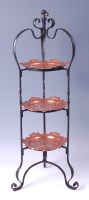 Lot 236 - An Arts & Crafts wrought iron three-tier cake...