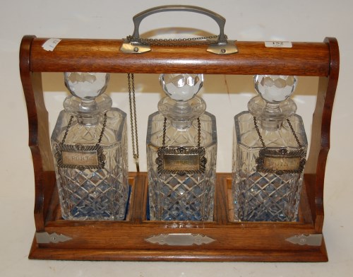 Lot 152 - A 1920s oak three bottle tantalus with silver...