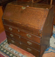 Lot 1449 - A George III oak slopefront three drawer...