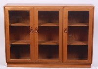 Lot 329 - An Ercol light elm three door bevel glazed...