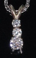 Lot 785 - A yellow metal and diamond three tier pendant,...