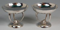 Lot 101 - A pair of Arts & Crafts hammered silver footed...