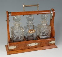 Lot 1025 - A circa 1900 oak and silver plated tantalus,...