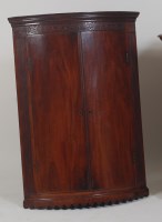 Lot 1034 - A George III mahogany bowfront hanging corner...