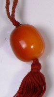 Lot 657 - A large amber bead, dia.3cm, on plaited fabric...