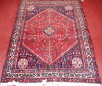 Lot 945 - A Persian Shiraz woollen rug, the ornate red...