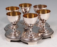 Lot 591 - A sterling silver egg cruet, the six cups each...