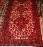 Lot 490 - A Persian woollen cream ground rug, the poled...