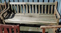 Lot 1169 - A teak slatted three-seater garden bench,...