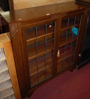 Lot 1482 - A 1930s oak double door lead glazed bookcase,...