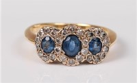 Lot 2653 - A three stone sapphire and diamond cluster...