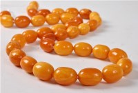 Lot 1126 - A butterscotch amber bead necklace, the...