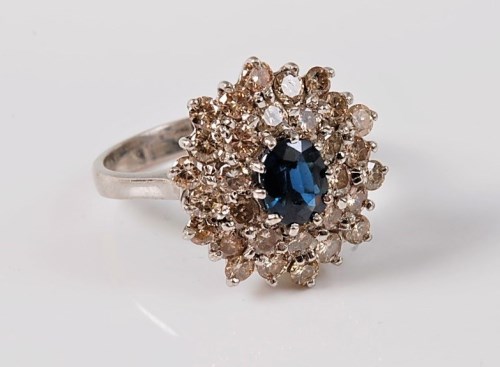Lot 1134 - An 18ct sapphire and diamond cluster ring, the...