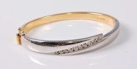 Lot 1161 - An 18ct bi-coloured diamond hinged bangle by...