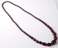 Lot 2523 - A faux 'cherry amber' bead necklace, the...