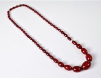 Lot 2524 - A faux 'cherry amber' bead necklace, the...