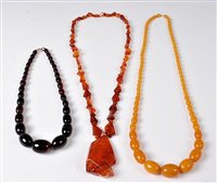 Lot 2526 - An amber necklace and two amber simulant...