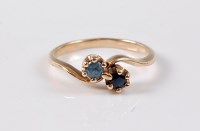 Lot 2631 - A two stone sapphire crossover ring, the dark...
