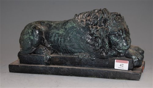 Lot 42 - A bronzed resin figure of a lion in recumbent...