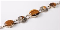 Lot 2504 - A tigers eye and silver bracelet, the central...