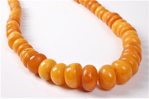Lot 2507 - A butterscotch amber bead necklace, the oval...