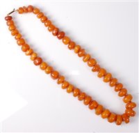 Lot 2180 - A butterscotch amber bead necklace, the...