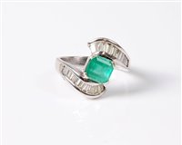 Lot 1213 - An 18ct emerald and diamond crossover ring,...