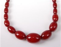 Lot 303 - A faux 'cherry amber' bead necklace, the...