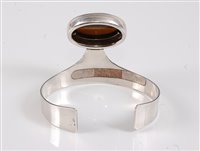 Lot 158 - A silver and tigers eye bangle, the oval...