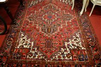 Lot 1133 - A Persian red ground woollen rug, having...
