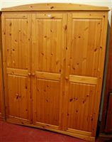 Lot 1142 - A modern pine effect three door wardrobe,...