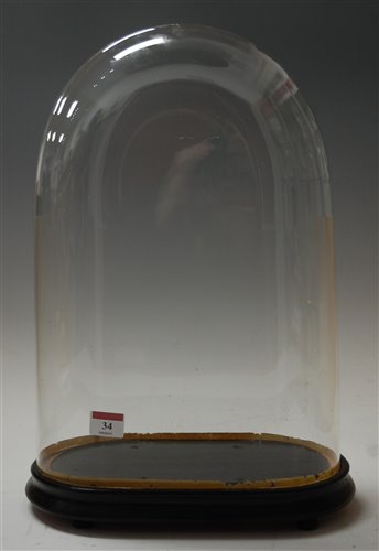 Lot 34 - A Victorian glass clock dome on ebonised oval...
