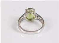Lot 1173 - A 14 peridot and diamond ring, the oval...