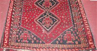 Lot 1560 - A Persian woollen rug, the red ground...