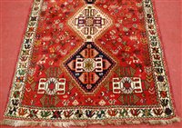 Lot 1562 - *A Persian woollen rug, the red ground...