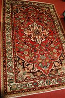 Lot 1204 - A Persian woollen red ground rug, having...