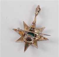 Lot 1218 - An emerald and diamond star pendant / brooch,...