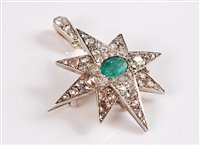 Lot 1218 - An emerald and diamond star pendant / brooch,...