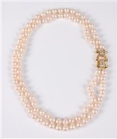 Lot 1211 - A two strand cultured pearl necklace with 18ct...