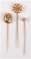 Lot 2508 - Three stick pins: to include an oval emerald...