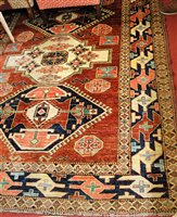 Lot 1195 - A Persian woollen Kazak rug, the red ground...