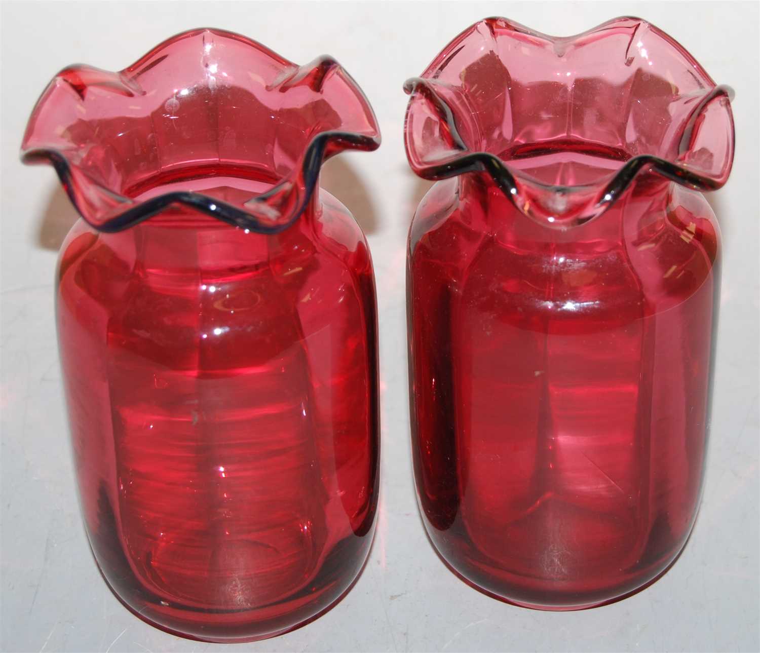 Lot 19 - A pair of cranberry glass vases, each having a...