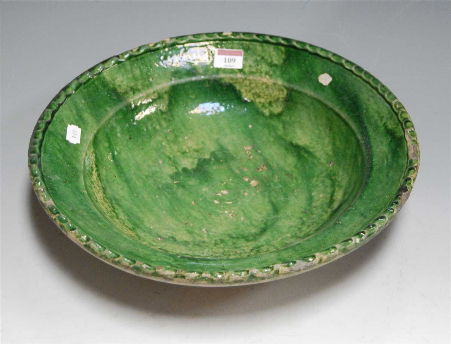Lot 109 - A 19th century green glazed pottery charger,...