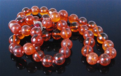 Lot 415 - A beaded and knotted faux amber long necklace,...