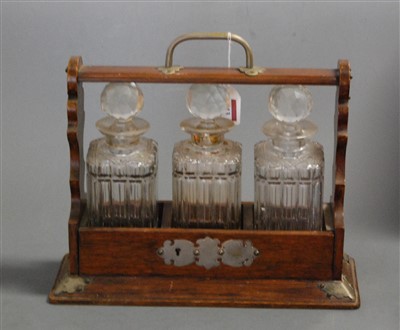 Lot 113 - A 1920s oak three bottle tantalus, with silver...